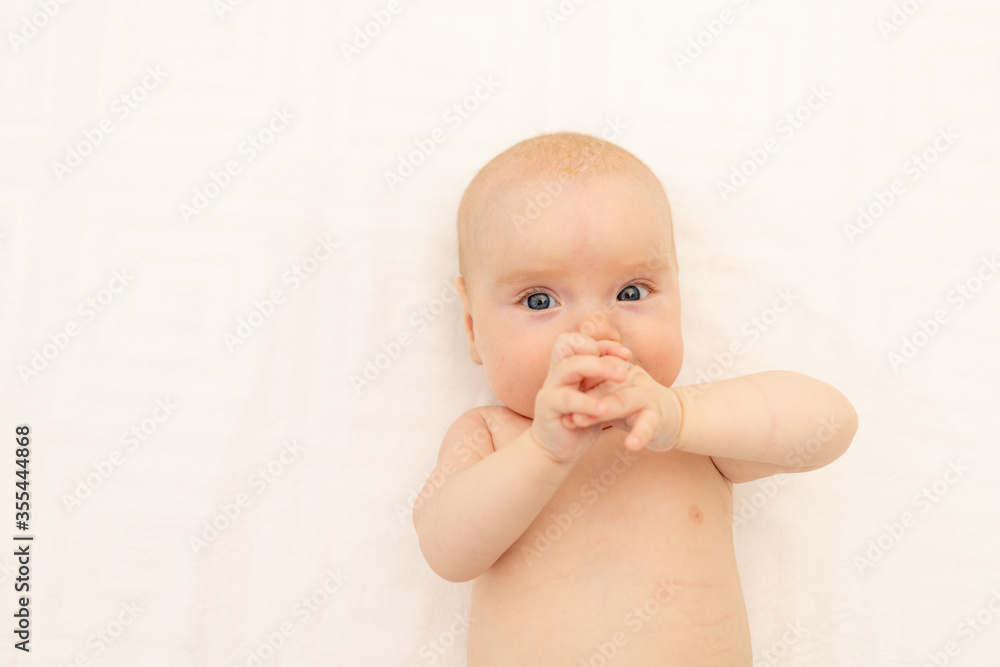 portrait of a child on a white background with his hands in his mouth. Bedding for children. 6 months. Healthy baby in the crib. Space for text portrait of a child on a white background with his hands in his mouth. Bedding for children. 6 months. Healthy baby in the crib. Space for text