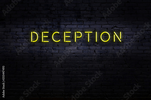 Fotografia Neon sign. Word deception against brick wall. Night view