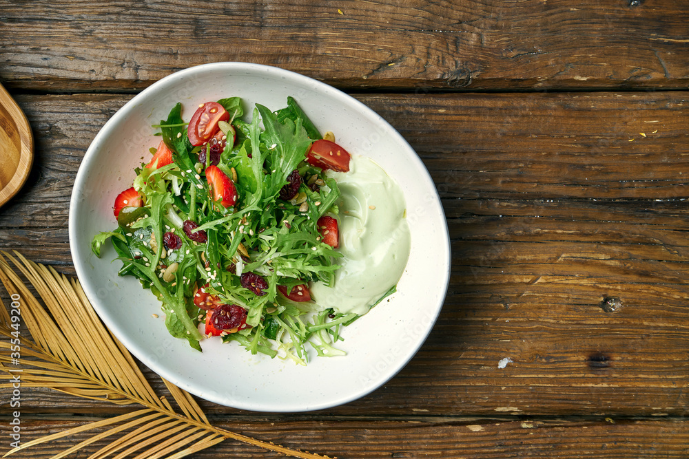 Vegetarian salad with cherry tomatoes, avocado mousse and strawberries in a bowl on a wooden background Vegetarian salad with cherry tomatoes, avocado mousse and strawberries in a bowl on a wooden background