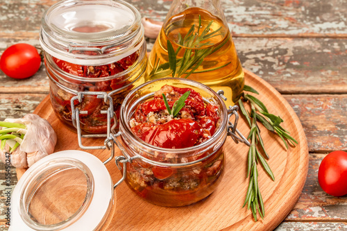 Sun dried tomatoes with fresh herbs and spices, olive oil in a glass jar. banner format
