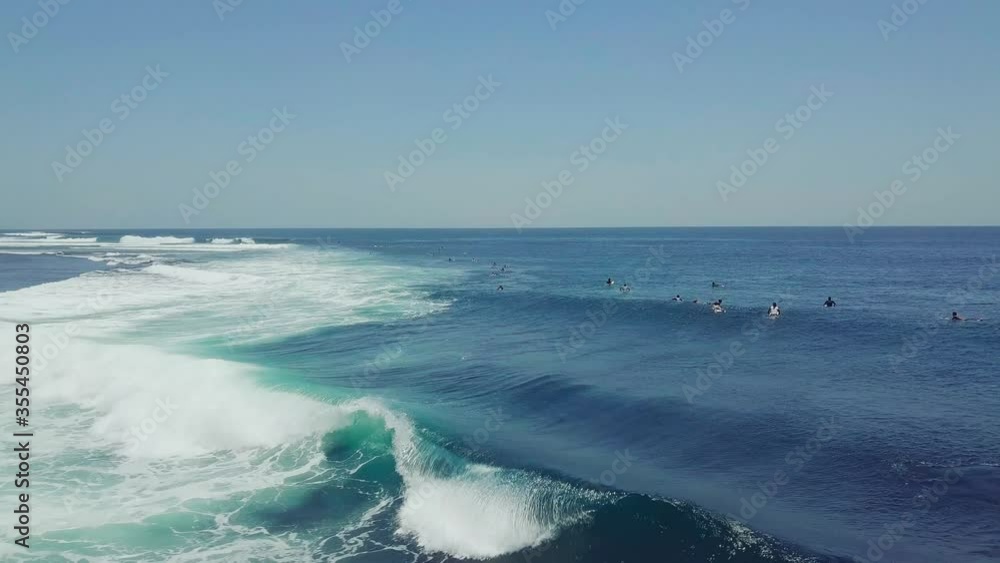 Group of surfers doing surf stunts and enjoys riding the waves on summer. Surfers in the blue ocean on a hot day, surfing session in Bali, Indonesia, people playing with the waves. Group of surfers doing surf stunts and enjoys riding the waves on summer. Surfers in the blue ocean on a hot day, surfing session in Bali, Indonesia, people playing with the waves.
