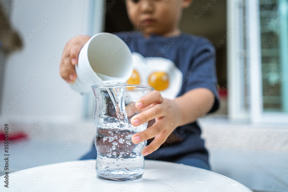little kid playing and pouring water to glass Stock Photo Adobe Stock