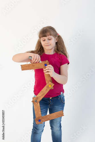charming girl repairs the number two from a wooden stick