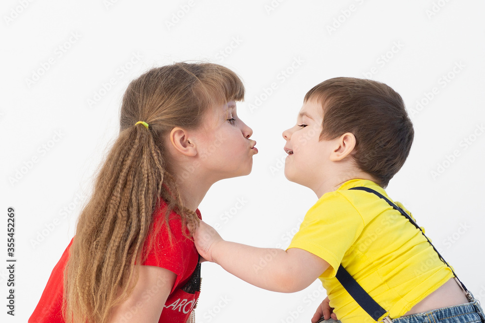 cute boy and girl in bright clothes kissing on a white background cute boy and girl in bright clothes kissing on a white background