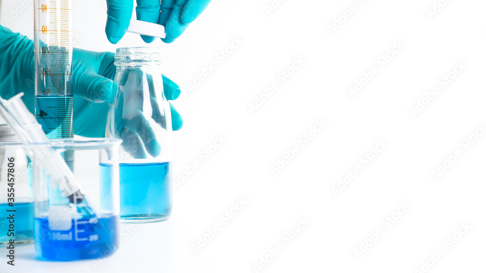 The scientist's hand is wearing blue gloves Holding the bottle and the lid of the bottle pretending to be closed, with experimental equipment placed White background with copy space concept laboratory The scientist's hand is wearing blue gloves Holding the bottle and the lid of the bottle pretending to be closed, with experimental equipment placed White background with copy space concept laboratory