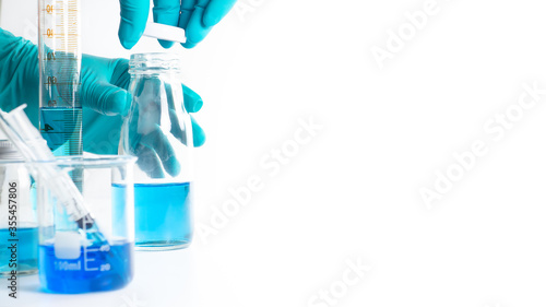 The scientist's hand is wearing blue gloves Holding the bottle and the lid of the bottle pretending to be closed, with experimental equipment placed White background with copy space concept laboratory