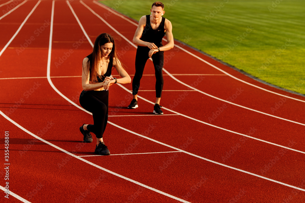 Beautiful sporty woman and young sporty man are ready to run on racetrack. 