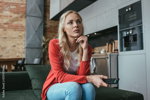 attentive woman watching tv while sitting on sofa at home