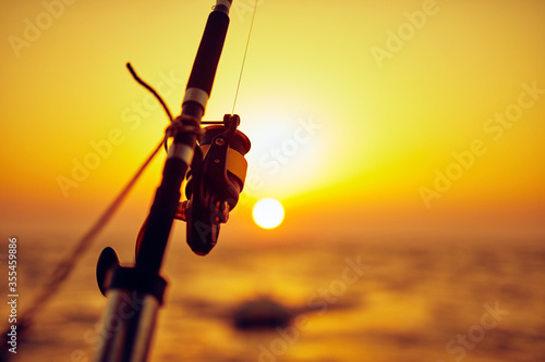 Obraz na plátně Fishing rod on a boat with sunset / sunrise and an ocean horizon.