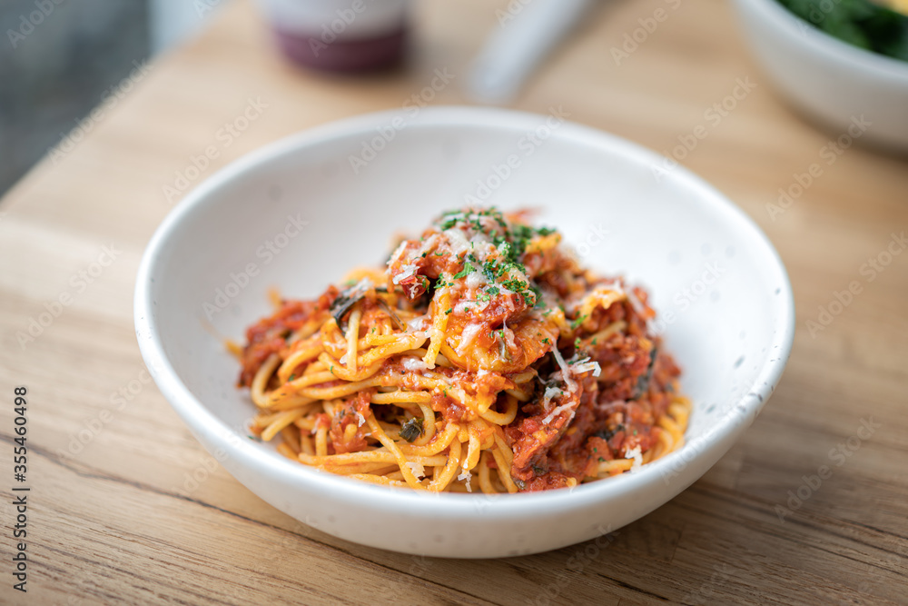A Pasta/Spaghetti with shrimp and cheese that served in the white luxury dish, placed on wooden table. Italian food and special dish photo. Select focus on the food surface. A Pasta/Spaghetti with shrimp and cheese that served in the white luxury dish, placed on wooden table. Italian food and special dish photo. Select focus on the food surface.