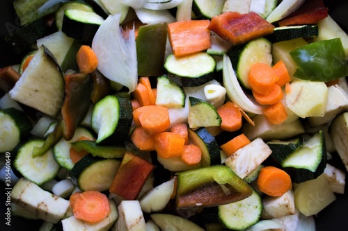 closeup of courgettes, carrots, peppers, onion, eggplants and garlic cut ready to be cooked as the basis for a vegetarian couscous 