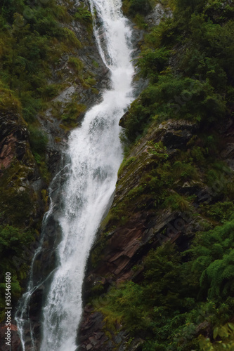 Stunning landscape of waterfall  lush green   rocky mountains and clouds. Monsoon trek to Ghangaria taken in August starts near Govindghat in Uttarakhand India.