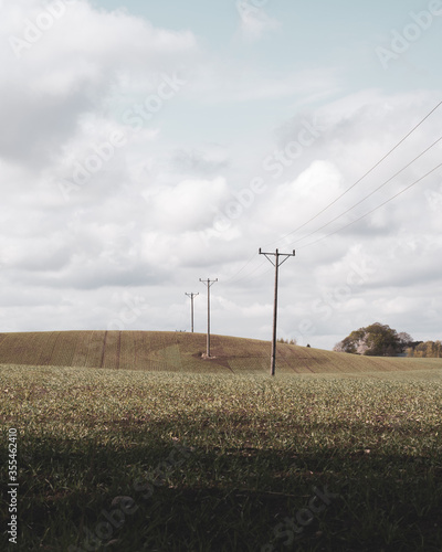 Some old electricity poles stands in the middle of a hilly farmland landscape in Skåne (Scania) in southern Sweden