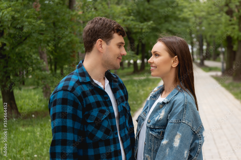 Obraz premium side view of happy couple looking at each other in park