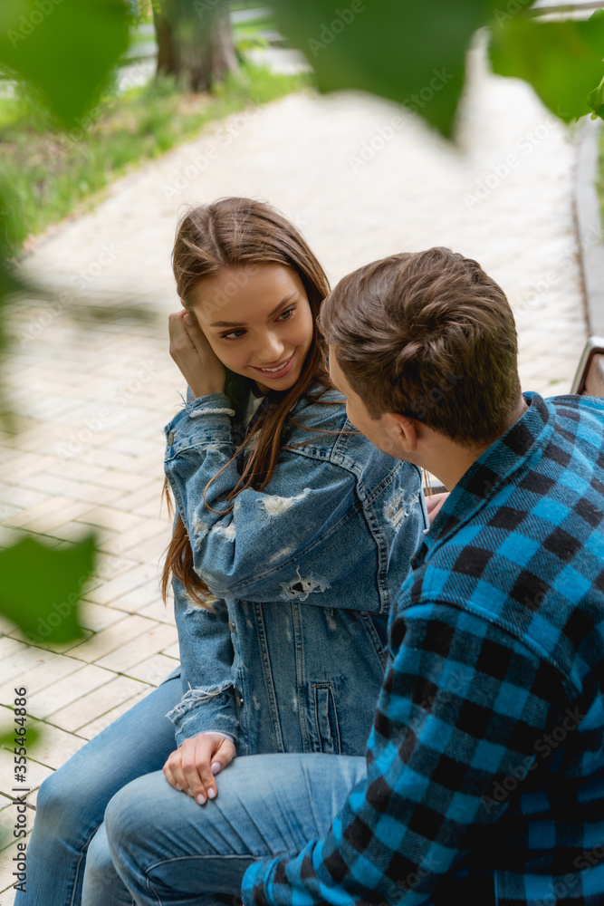 selective focus of attractive girl touching hair while flirting with boyfriend selective focus of attractive girl touching hair while flirting with boyfriend