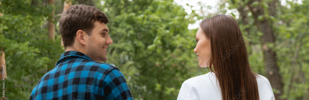 horizontal image of handsome boyfriend and pretty girlfriend looking at each other in park horizontal image of handsome boyfriend and pretty girlfriend looking at each other in park