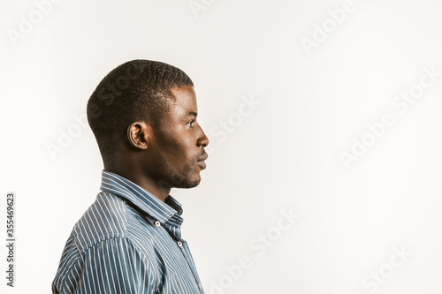 Young African man on white background. Profile view of serious Afro American student or businessman looking at right side with textspace or copy space. Toned image.