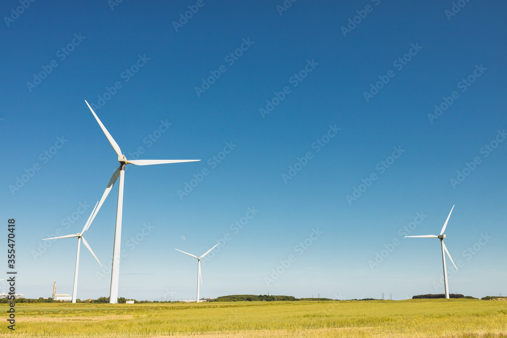Windfarm generating clean renewable energy on sunny summer day with clear blue sky global warming Windfarm generating clean renewable energy on sunny summer day with clear blue sky global warming