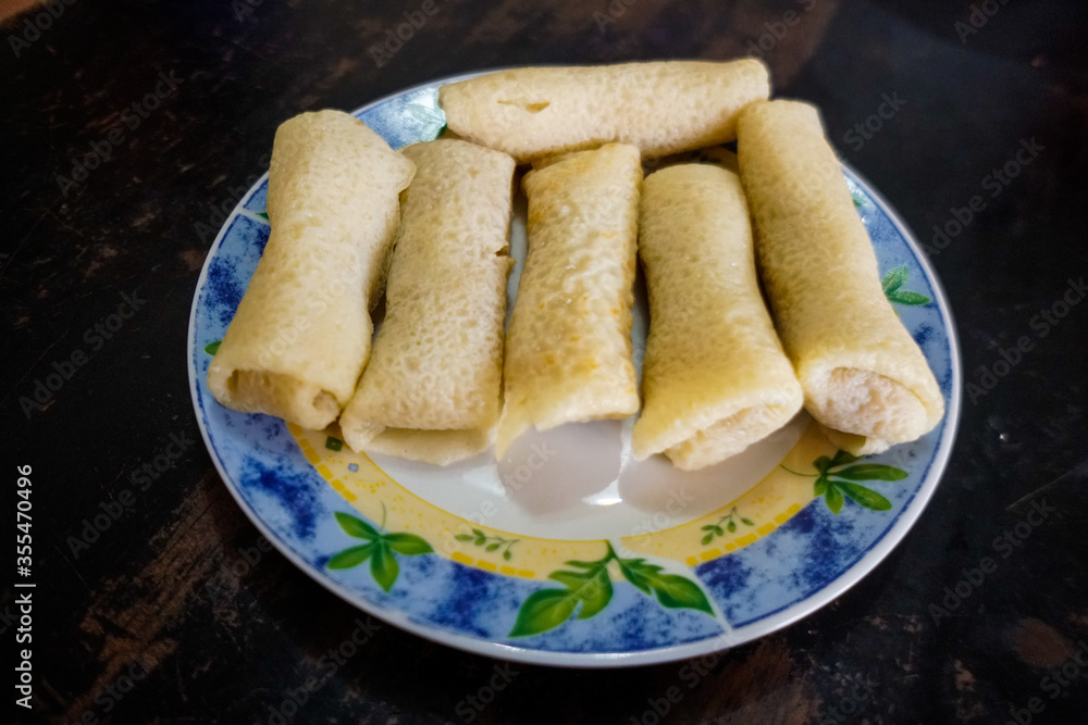 Dadar gulung/kuih ketayap is a popular traditional kue of sweet coconut pancake. It is often described as an Indonesian coconut pancake. Isolated on white background. 