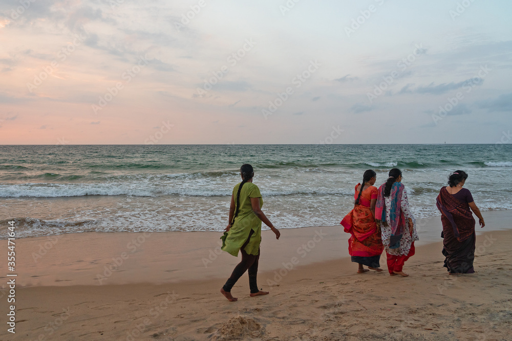 Indian women in traditional dresses walking by ocean beach, Sri Lanka