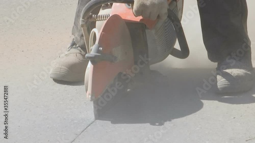 Repair work on the road. A worker saws asphalt.