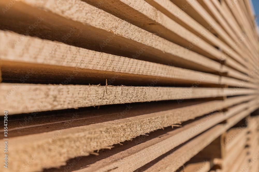 Piles of wooden boards in the sawmill, planking. Warehouse for sawing boards on a sawmill outdoors. Wood timber stack of wooden blanks construction material. Industry. Piles of wooden boards in the sawmill, planking. Warehouse for sawing boards on a sawmill outdoors. Wood timber stack of wooden blanks construction material. Industry.