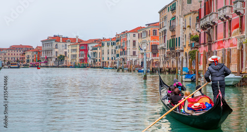 Fotografiet Venetian gondolier punting gondola through green canal waters of Venice Italy