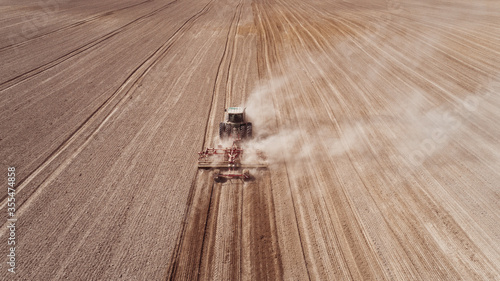 Farmers cultivating. Tractor makes vertical tillage. Aerial view