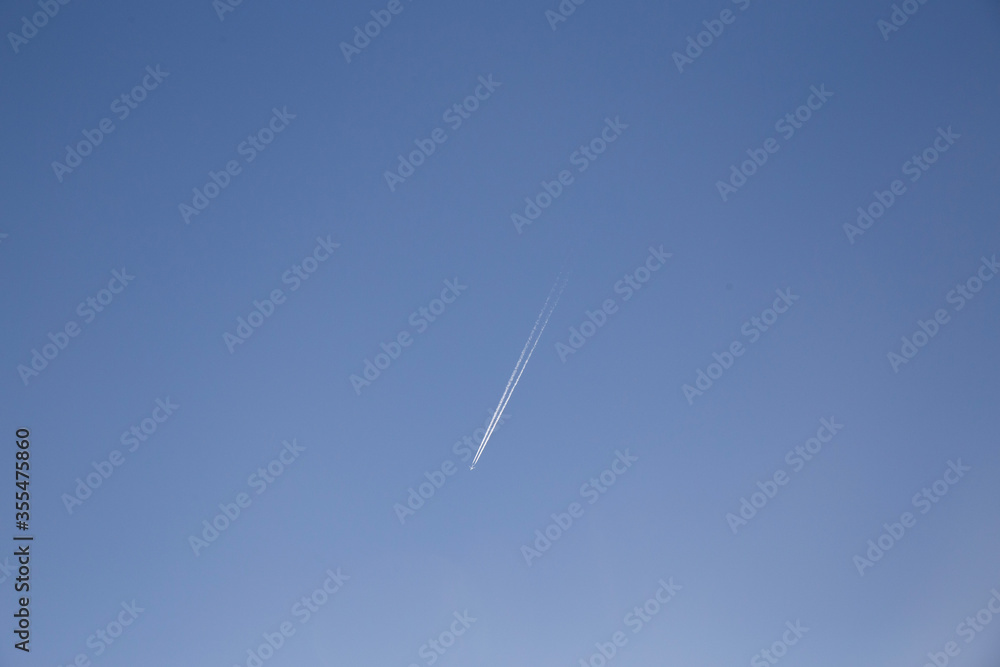 Airplanes leaving diagonal trace on a clear blue sky. Plane trail concept, traveling environmental issues Airplanes leaving diagonal trace on a clear blue sky. Plane trail concept, traveling environmental issues