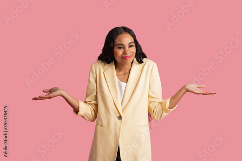 Obraz na plátně Portrait of an young woman in yellow jacket with arms out and shoulders up, and