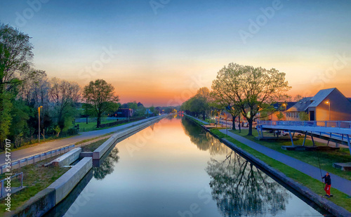 Dramatic and mesmerizing colorful sunset or sunset sky with horizon over Flemish canal in Belgium