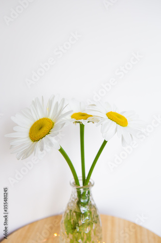 Daisies in vase on a old wooden table © Artsaba Family