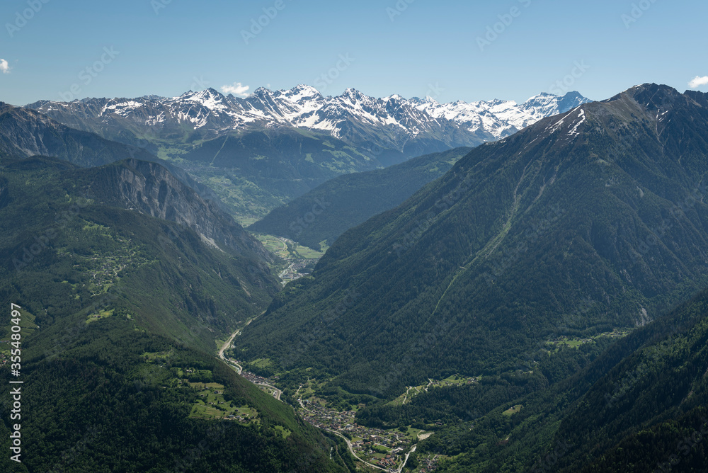 Alpine mountains, meadows and forests on a background of blue sky with clouds.