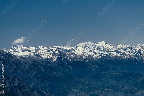 Alpine mountains, meadows and forests on a background of blue sky with clouds. © Andrew
