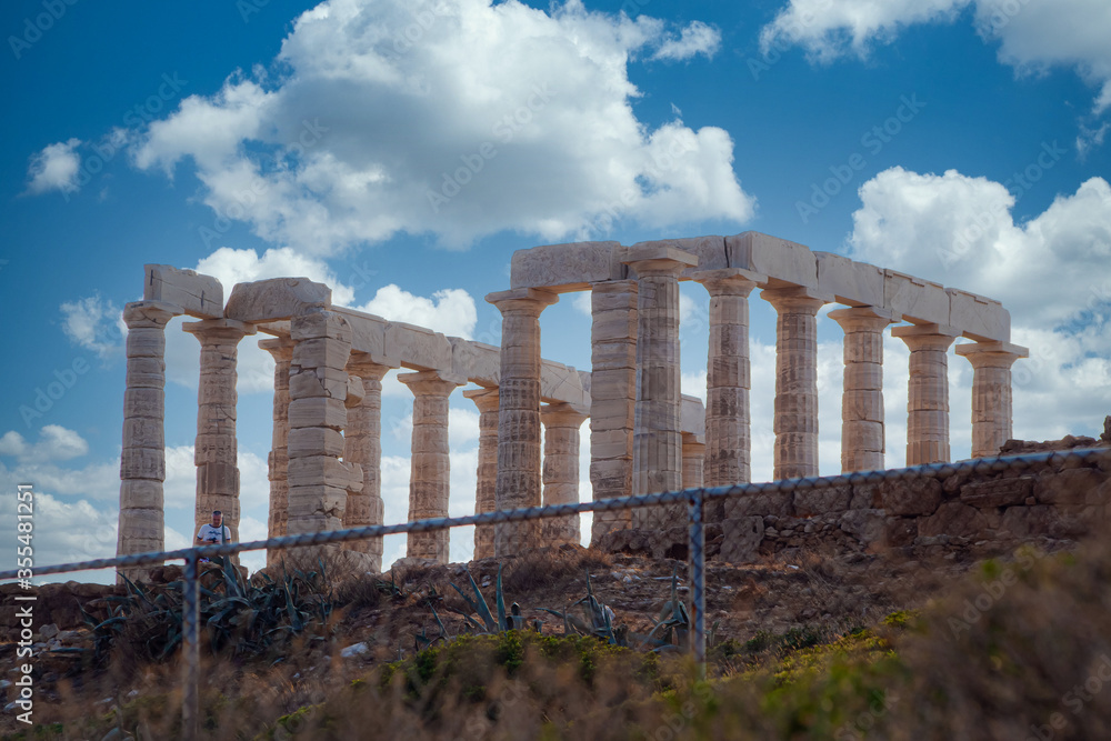 The Temple of Poseidon at Sounio, Greece against a cloudy sky, shot taken from across the bay