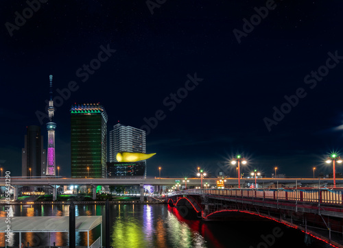 Night view of the Azuma bridge on Sumida river leading to the Tokyo Skytree and Olympic golden flame shape sculpture of the Asahi Beer Headquarter Building in Asakusa. photo