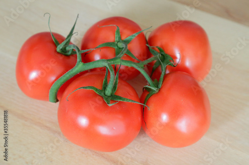 Fresh tomatoes, on wooden table with natural light