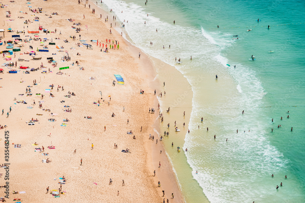 Drone view of ocean beach with colorful umbrellas. Beautiful long ocean beach with umbrellas and people. 