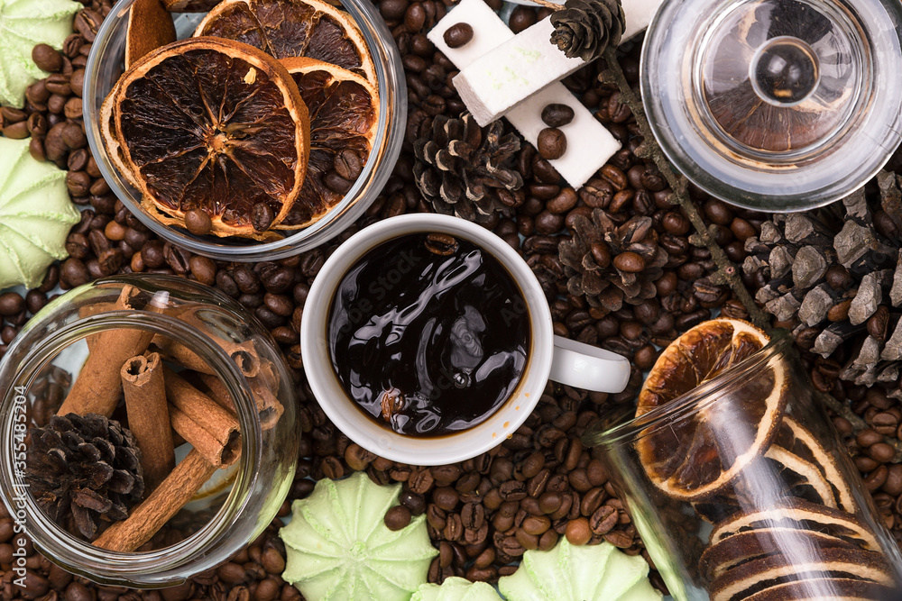 A white Cup of coffee on coffee beans, on a light blue wooden table. Wooden table. Fir cones on the table. Green marshmallows and white marshmallows. Dried citrus. Brown background. A white Cup of coffee on coffee beans, on a light blue wooden table. Wooden table. Fir cones on the table. Green marshmallows and white marshmallows. Dried citrus. Brown background.