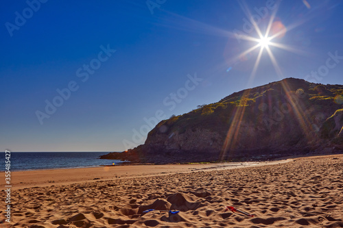 Fototapeta Naklejka Na Ścianę i Meble -  Image of La Greve de Lecq in the mornig sumer sunshine at low tide with sandy beach and clear blue sky. Jersey, Channel Islands, Uk
