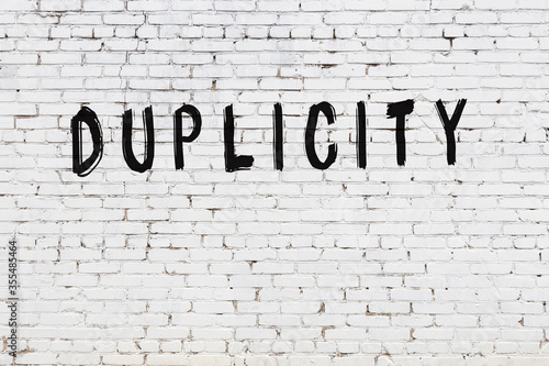 White wall with black paint inscription duplicity on it