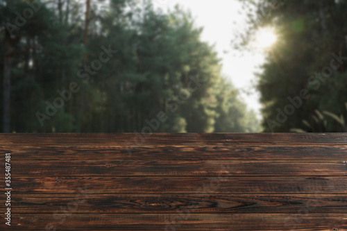 Wooden table against beautiful forest. Mockup. Sunny day