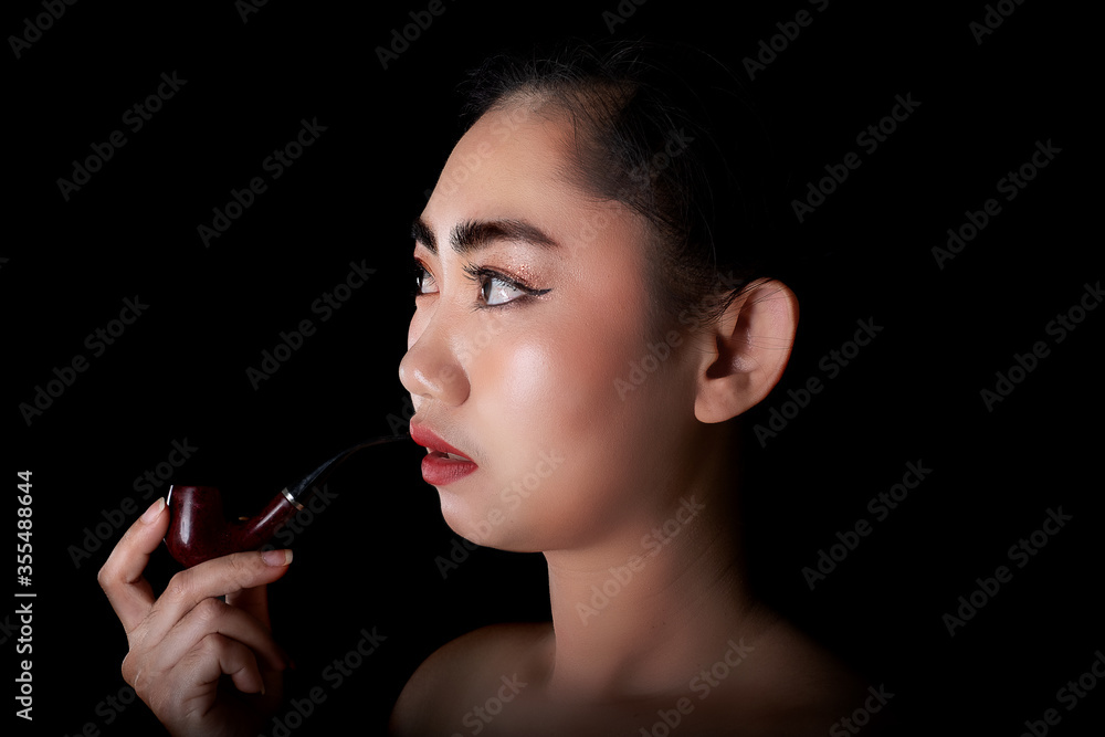 Obraz premium Portrait beautiful Asia young women with a smoking pipe tobacco on the black background