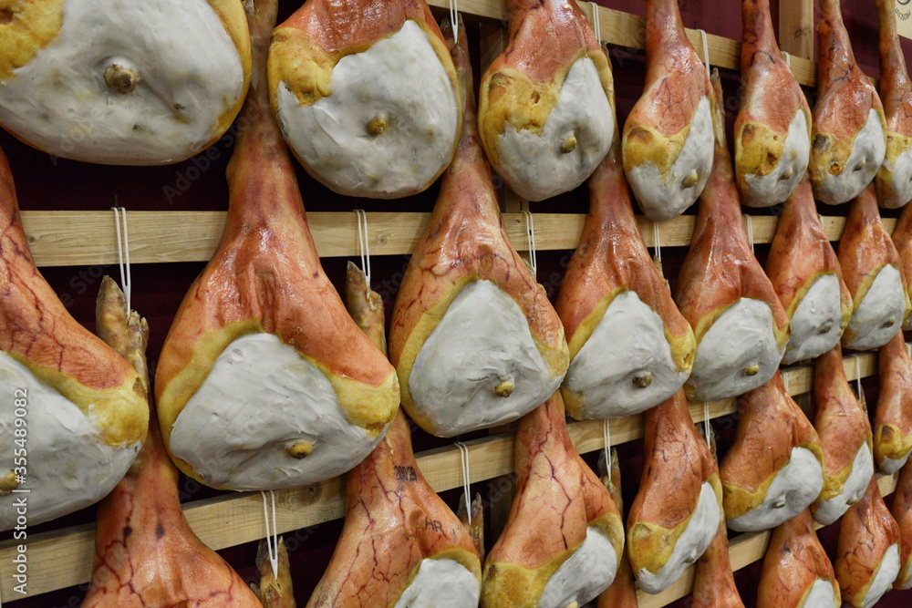 Italian food specialty San Daniele raw hams hung in a food fair stand 