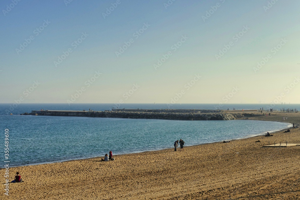 Panoramic view of sand beach inlet and pier with few people