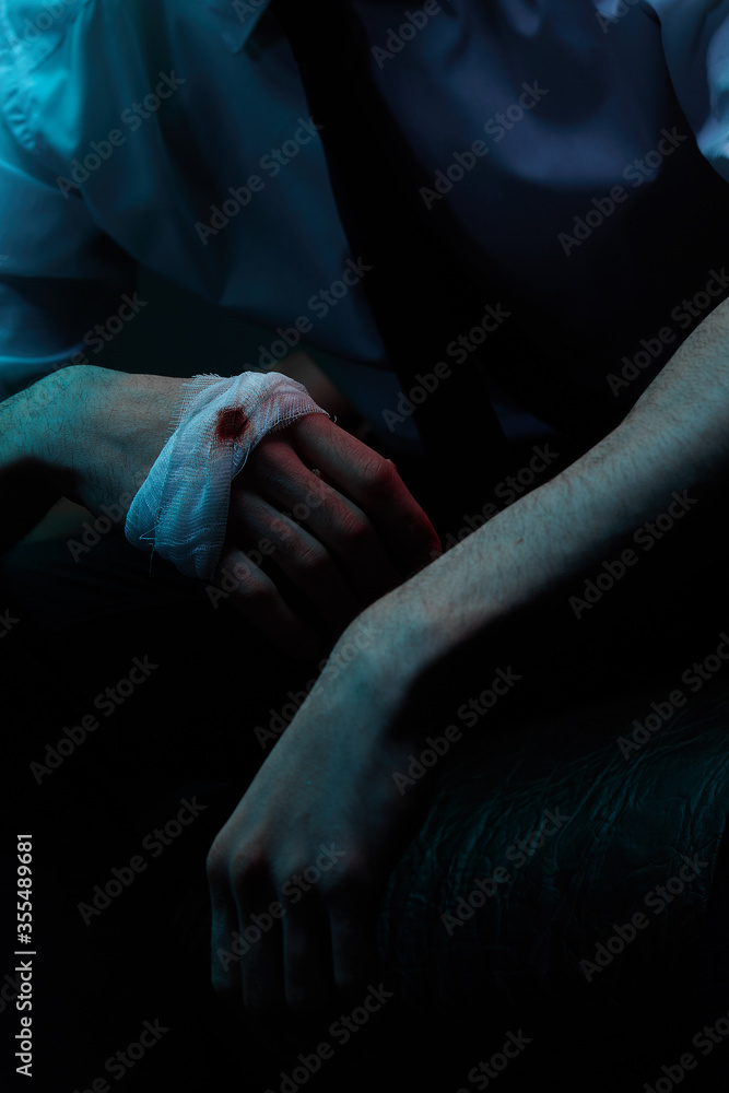 Portrait of a man in blue and red contrasting lighting in a white shirt with a tie and a facial injury, posing sitting in a leather chair. Close-up of a bandaged hand. Futuristic neon lighting