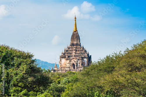 View to the Facade of the Building Shwegugyi Temple in Bagan, Myanmar. Copy space for text, with Trees and blue Sky
