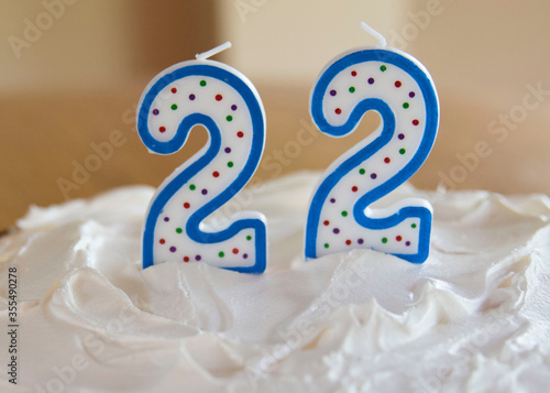 Happy 22nd birthday.  Birthday cake with a 22 candle in white frosted cake. 