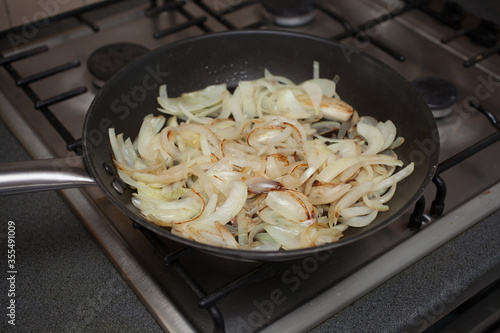 Sliced brown onions frying in a saucepan on a gas oven photo