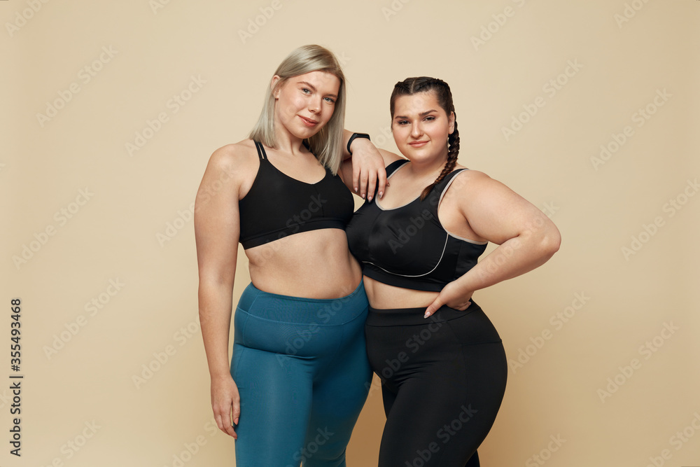 Foto de Body Positive. Plus Size Models Portrait. Confident Full-Figured  Women In Sport Clothes Against Beige Background. Fitness For Active  Lifestyle. do Stock
